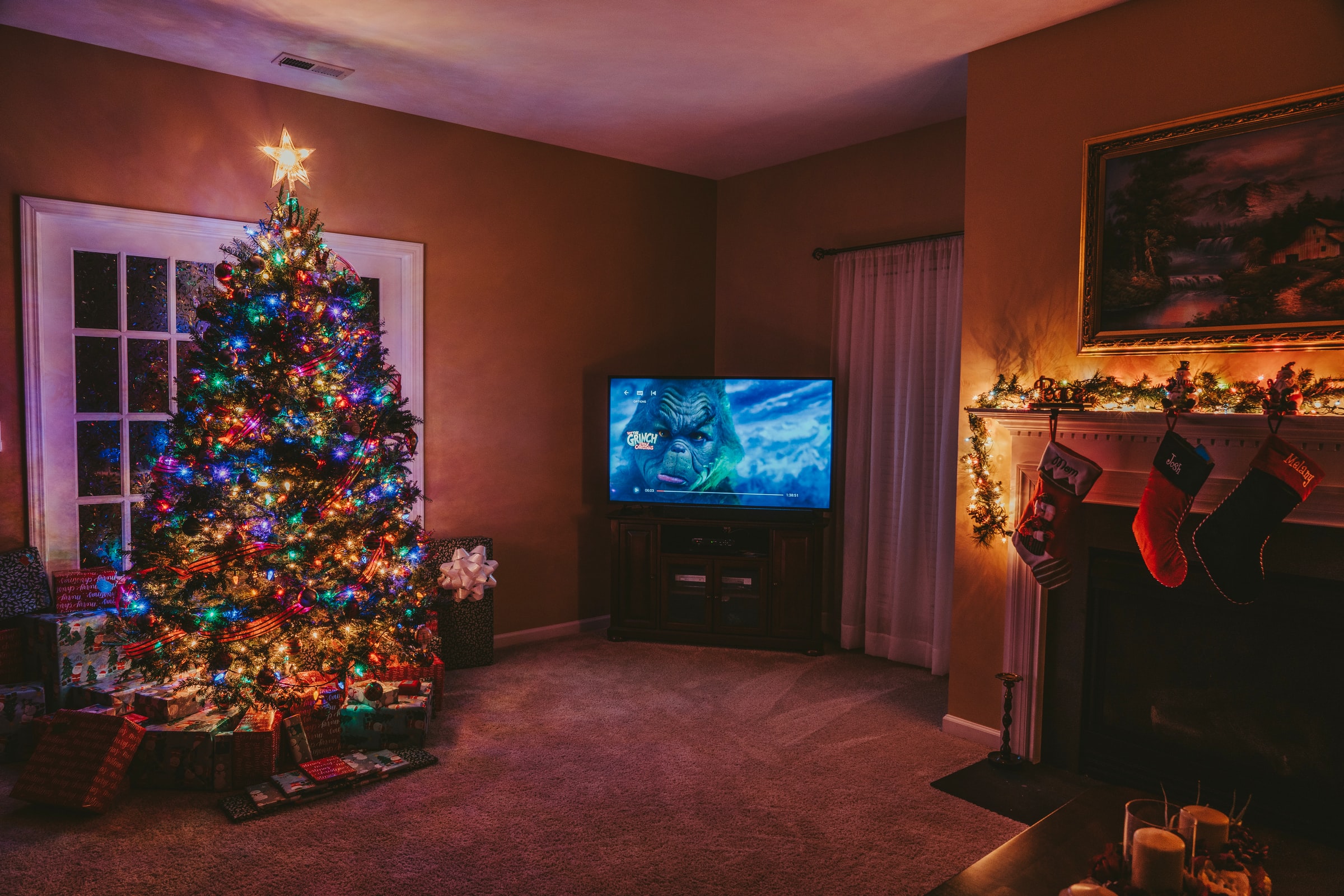 A decorated Christmas tree in a living room. Gifts are placed at the foot of the tree.